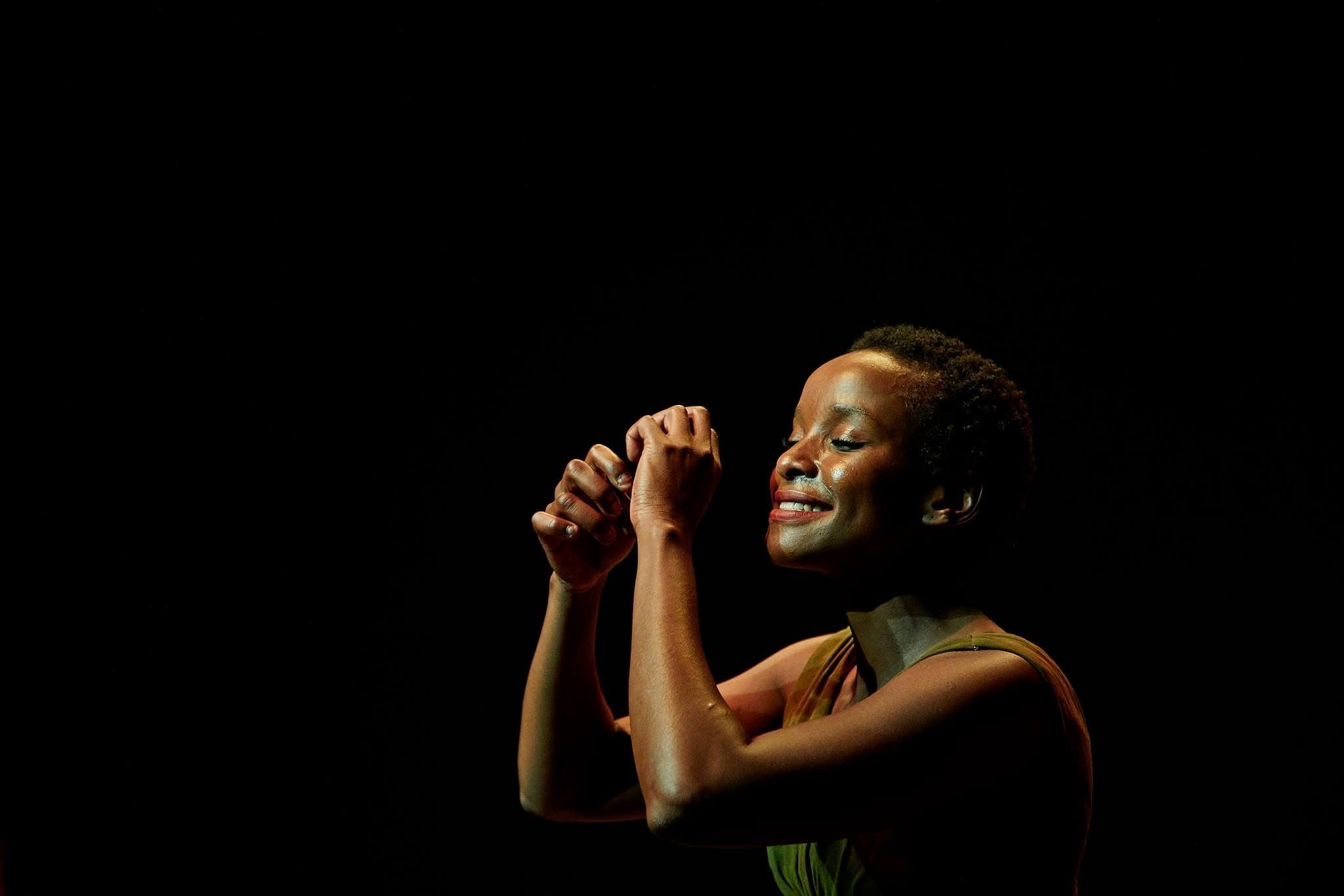 Close portrait of a performer in green against darkness.