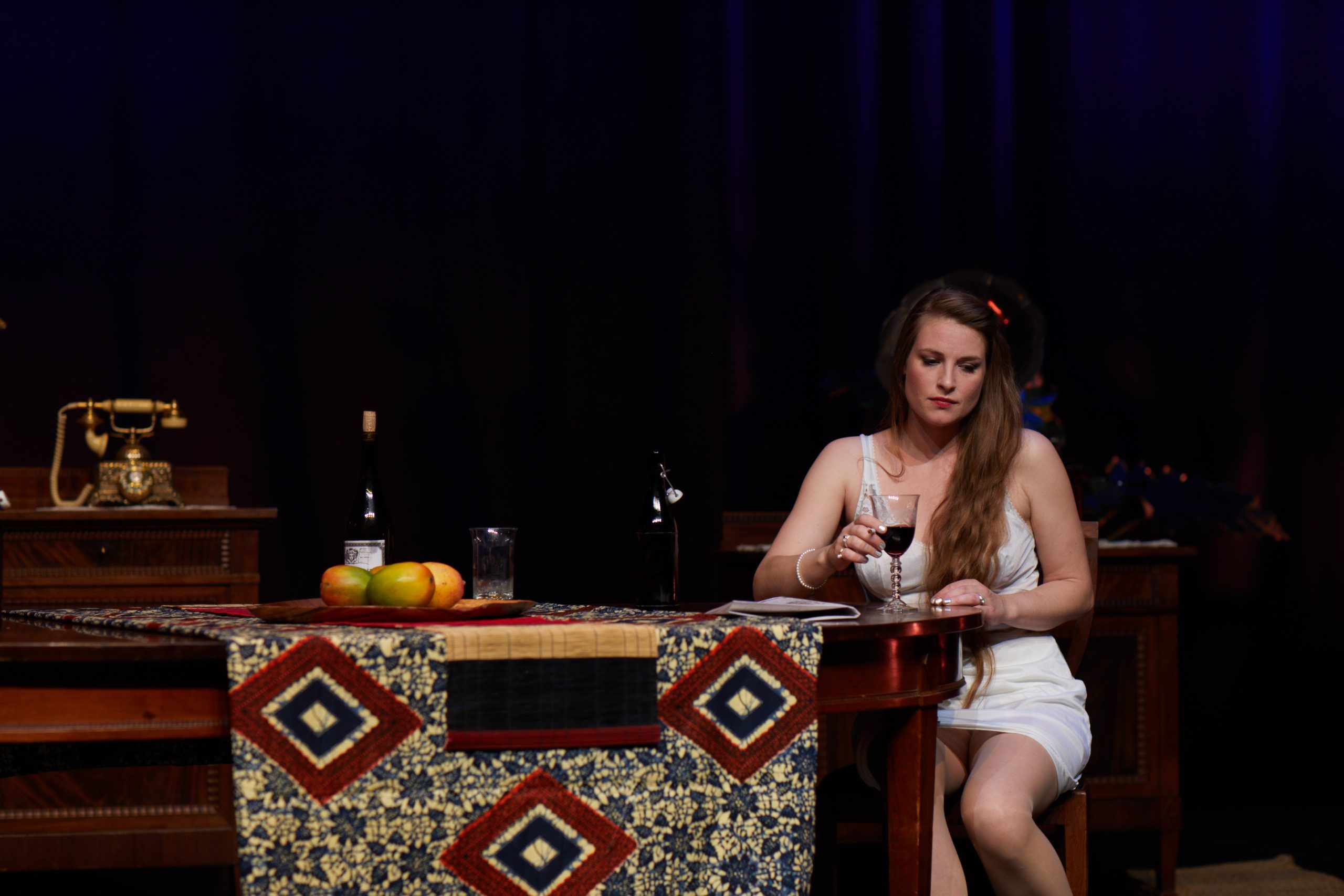 Julie seated at a table with a glass of wine in Miss Julie’s Happy Valley.